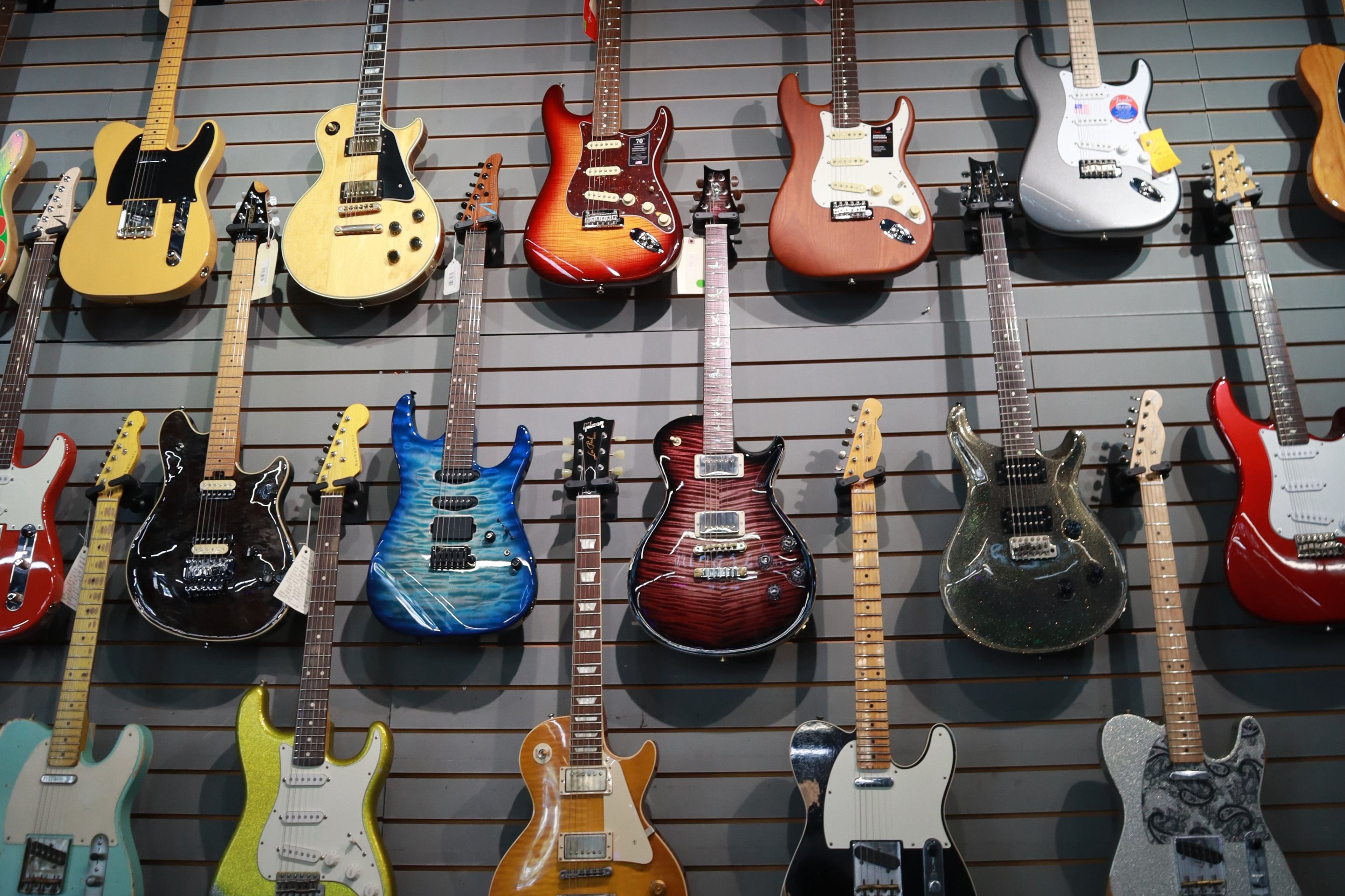 Collection of electric guitars displayed against a dark wall.